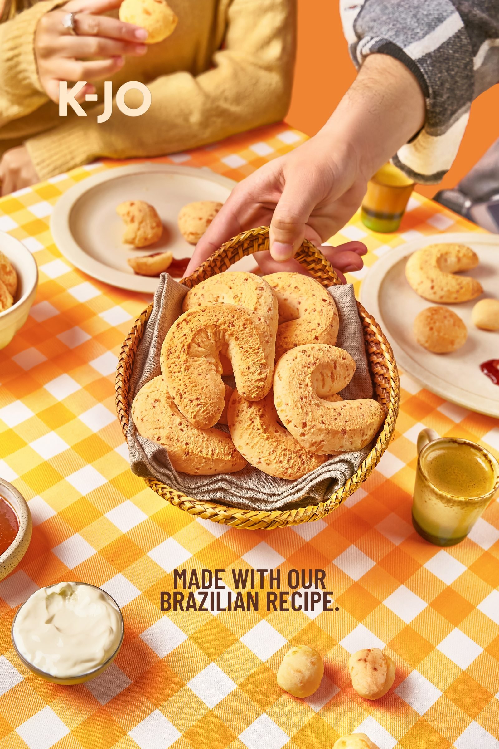 Basket of cheese bread rings on an orange checked tablecloth, a hand reaching in