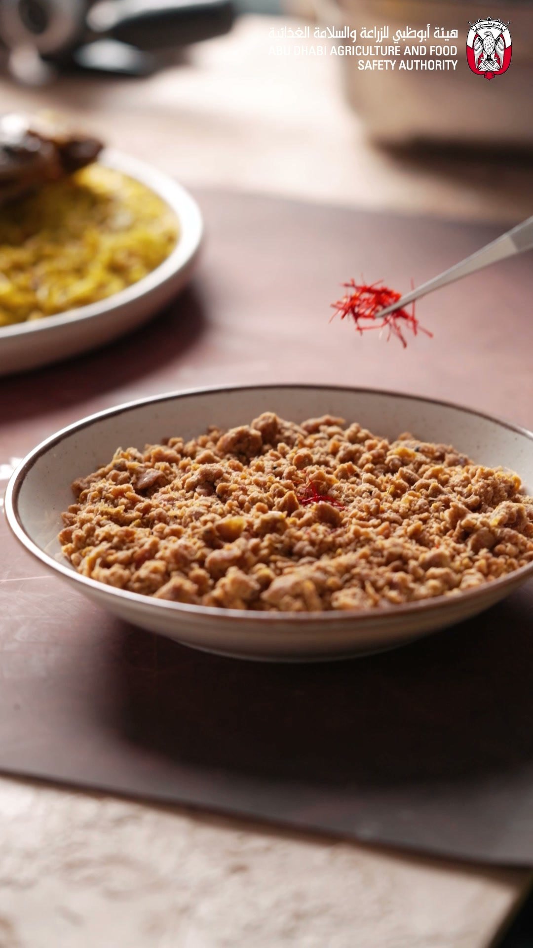 Saffron threads falling onto a bowl of minced meat and toasted vermicelli