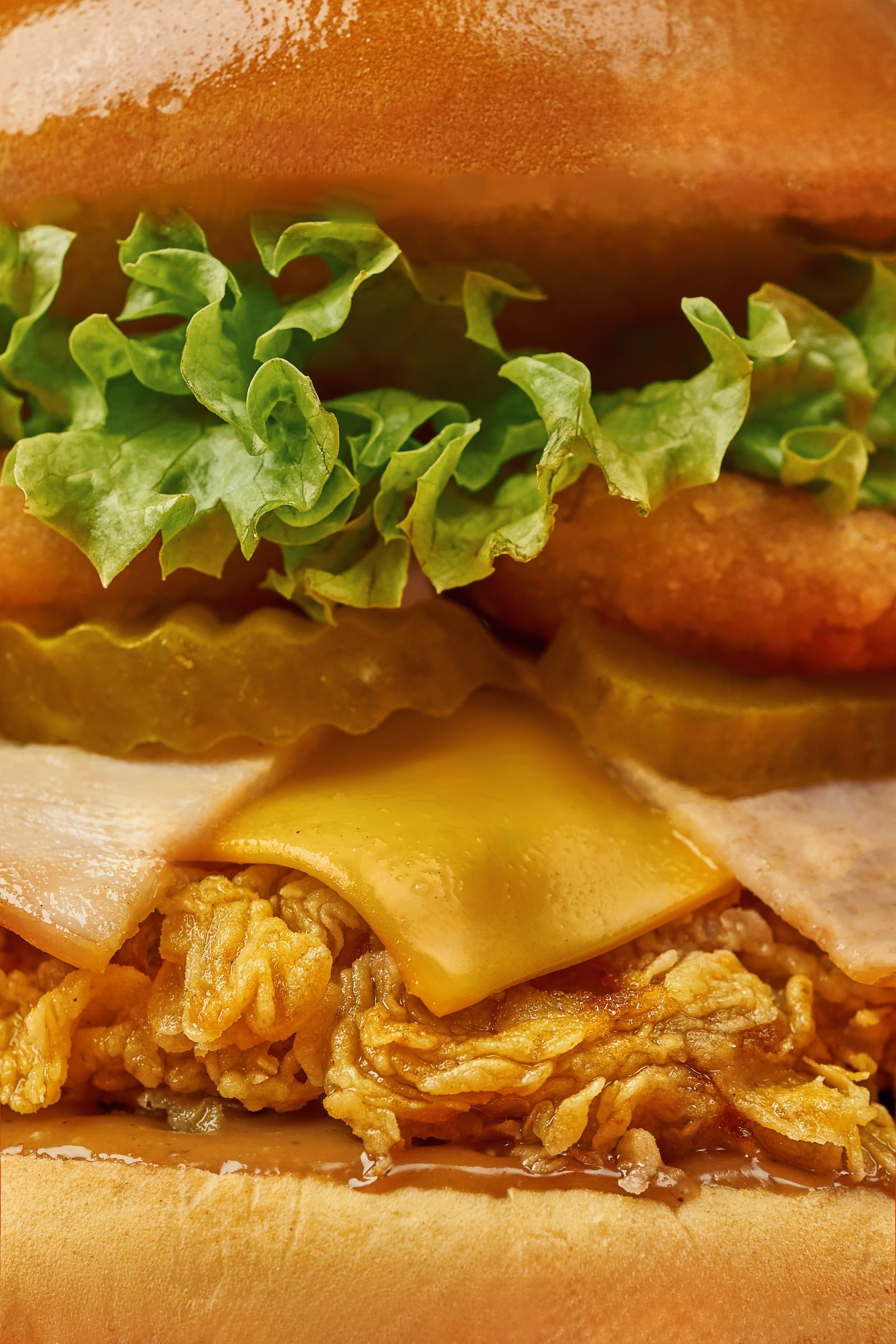 Close-up of a fried chicken sandwich with melted cheese and frilled lettuce