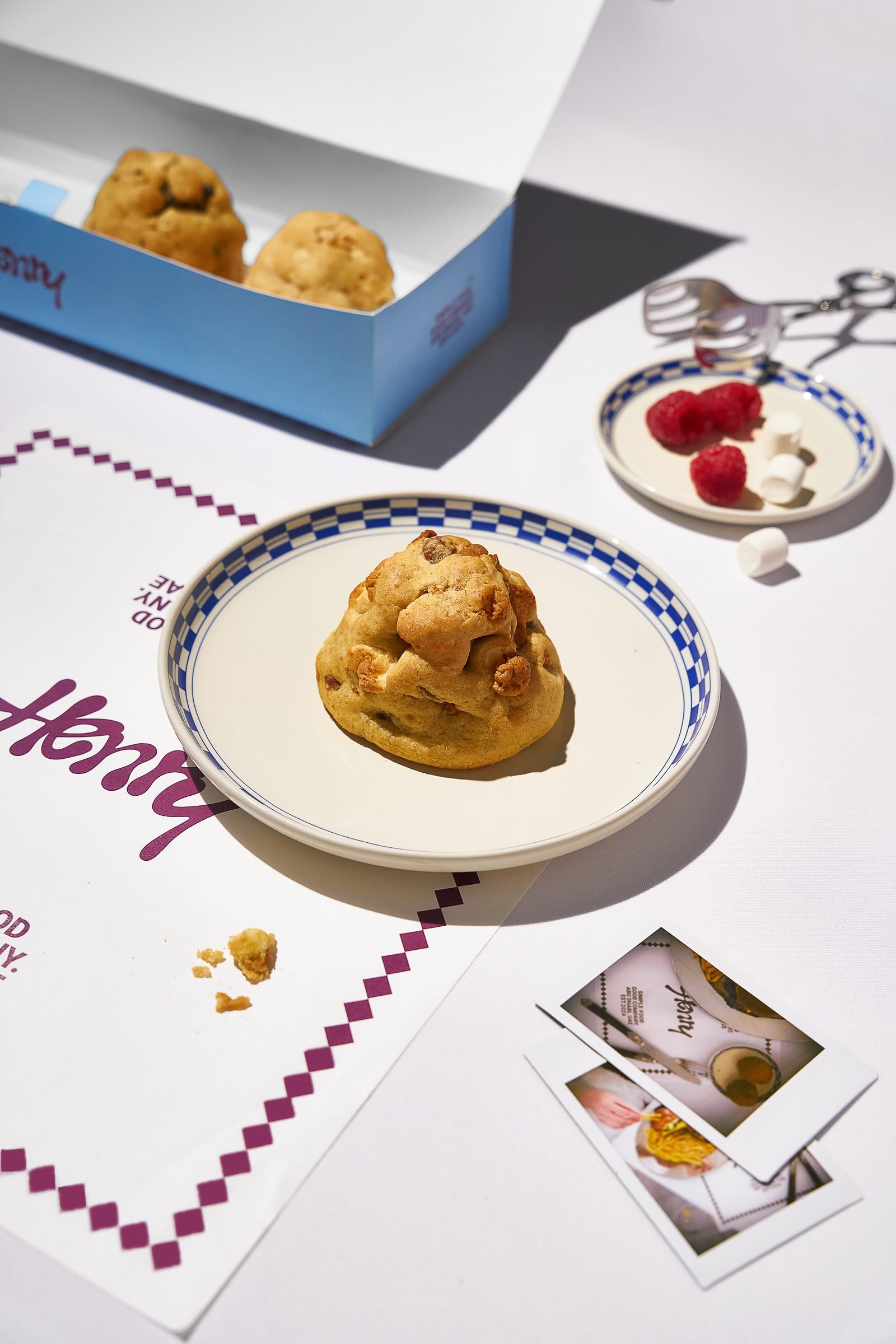 Cream puff on a Henry plate beside an open pastry box and a strip of photographs