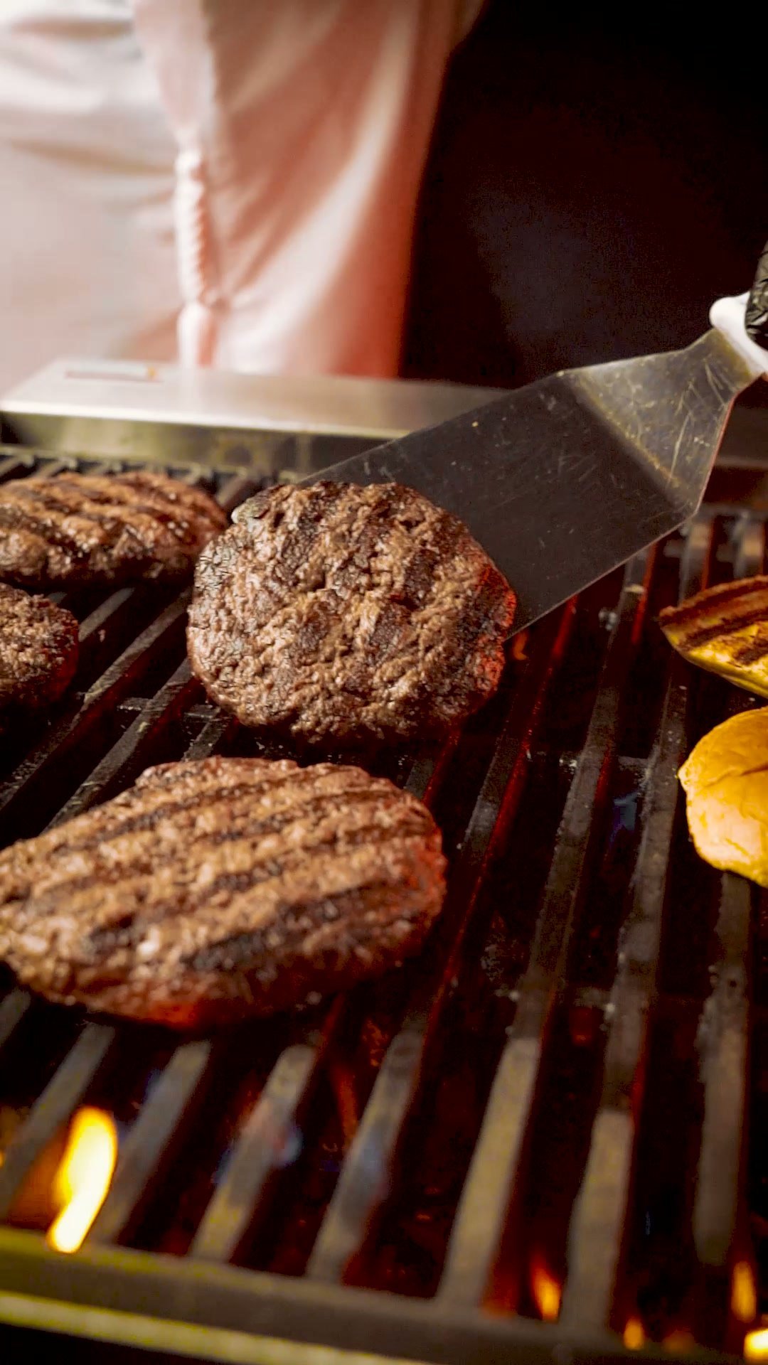 Beef patties on a grill being lifted with a spatula