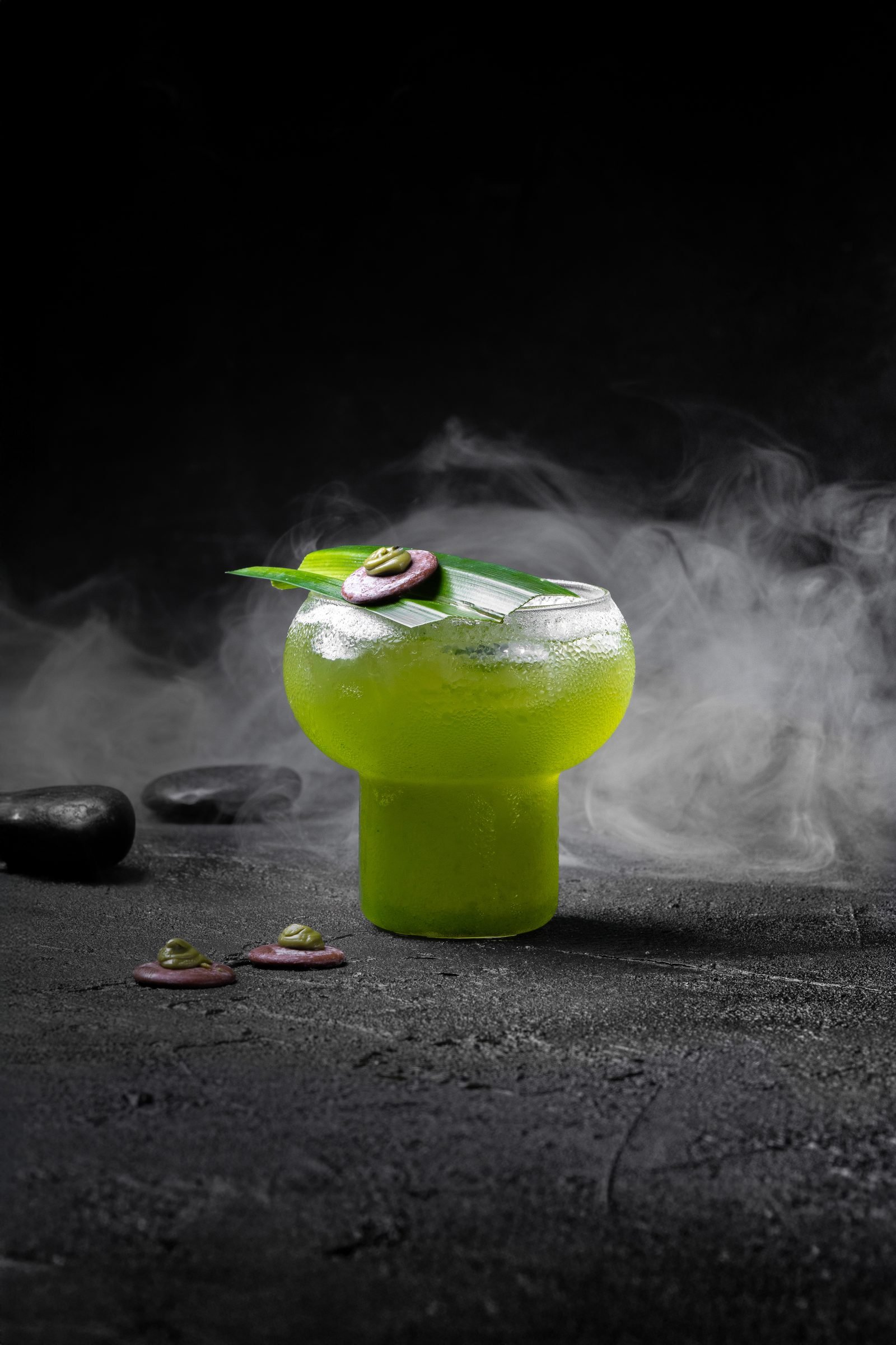 Green cocktail on a stone slab in drifting dry-ice smoke