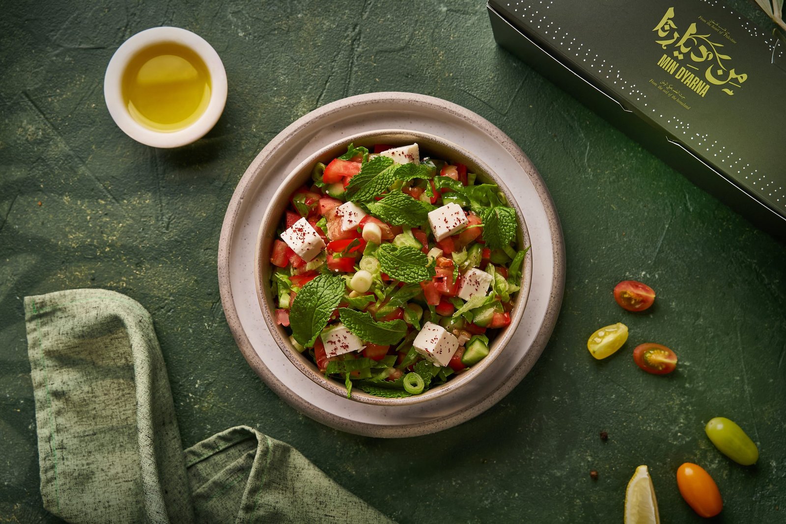 Fattoush with feta and tomatoes in a stone bowl, olive oil and cherry tomatoes beside it