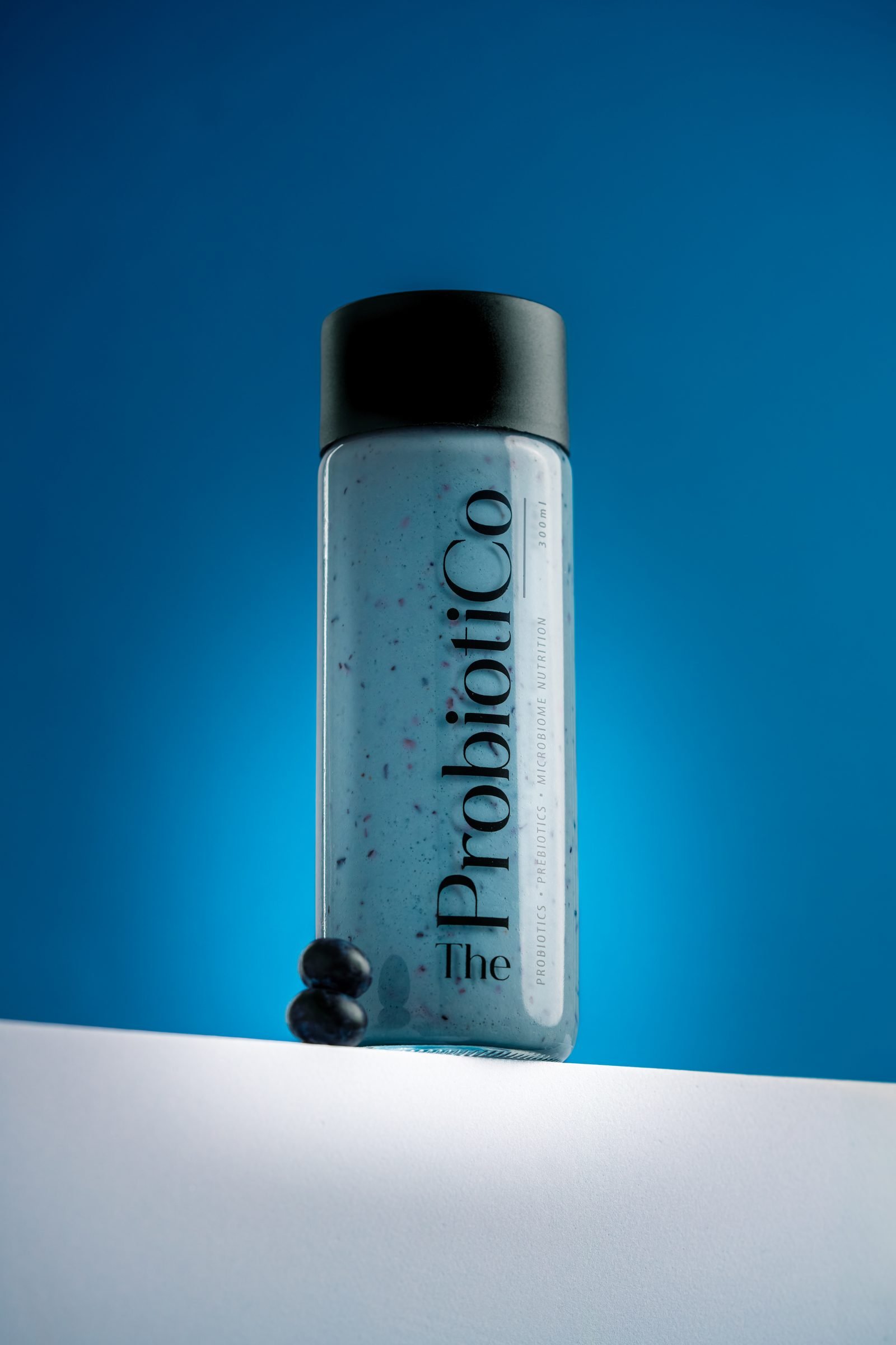 Bottle of blue Probiotico drink on a white ledge against a deep blue backdrop