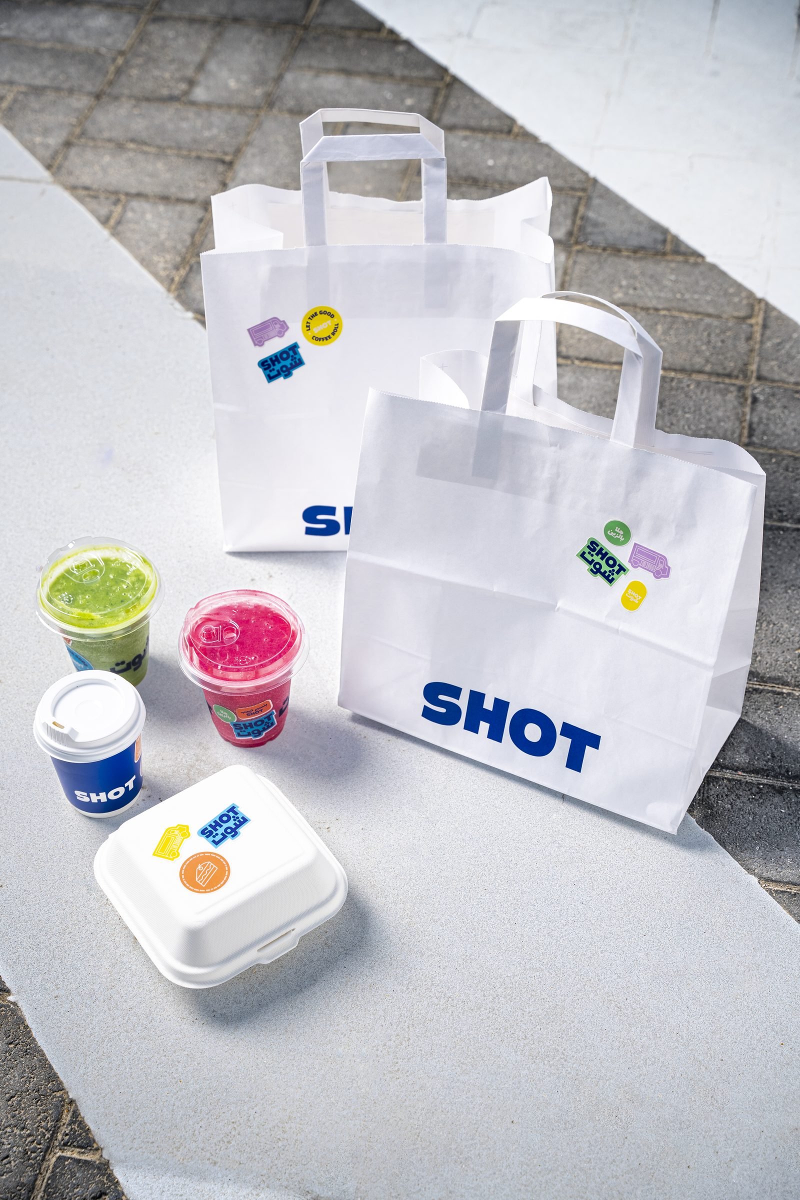 Shot takeaway bags, juices and a dessert cup on a concrete step