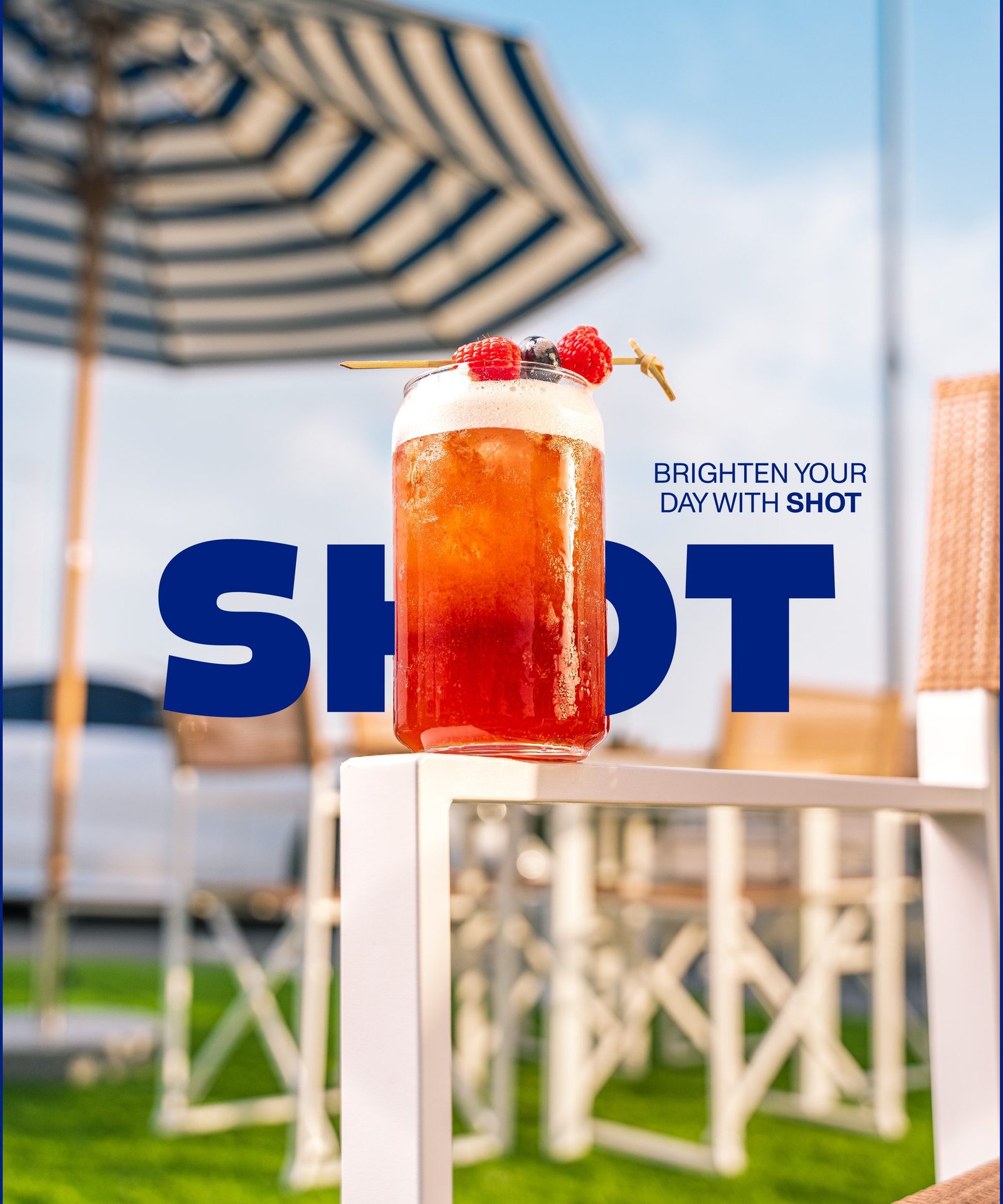 Iced fruit drink on a table under a striped parasol, the Shot wordmark behind it