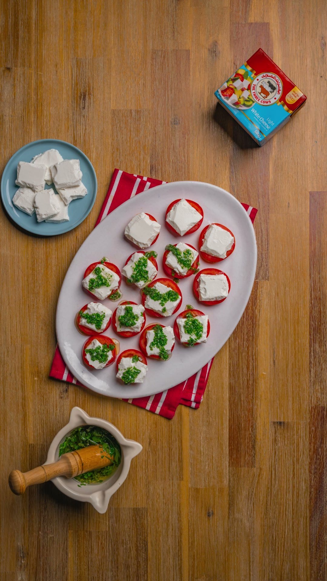 Overhead of cream cheese canapes with herbs on an oval plate, a TTC pack beside them