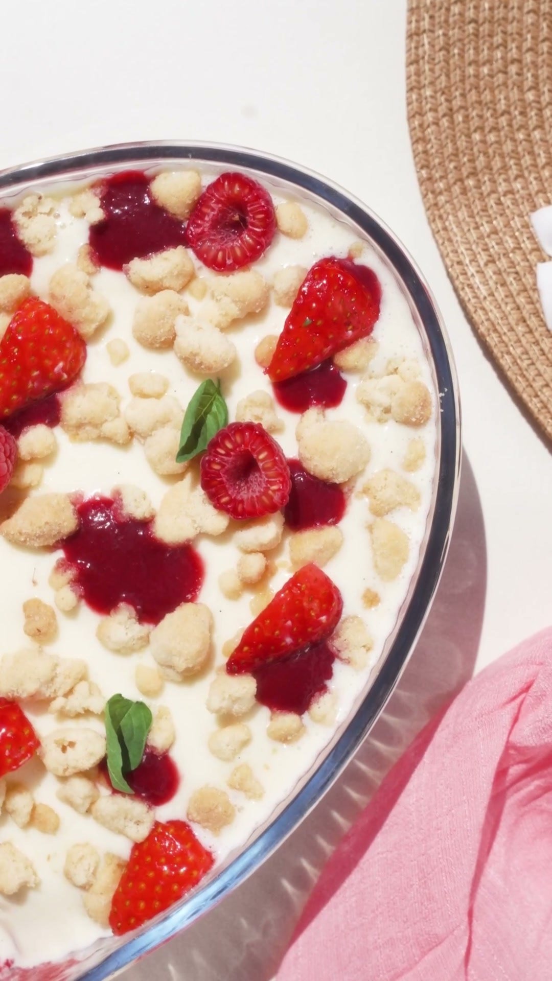Tray of strawberry and raspberry tiramisu topped with basil, on a pink cloth