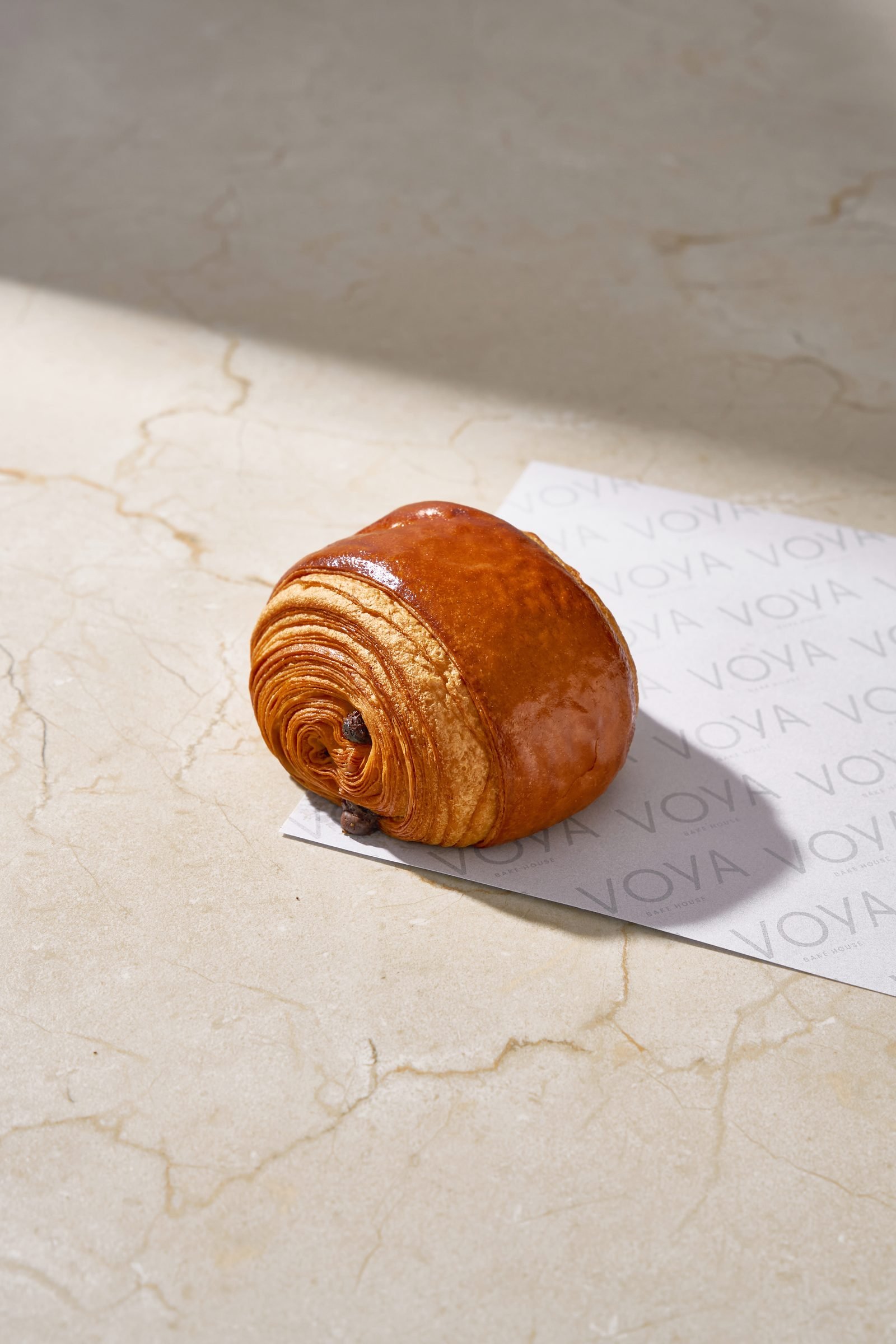 Glazed pain au chocolat on Voya paper on cream marble