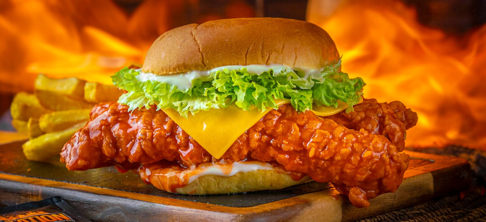 Hot chicken burger with cheese and lettuce over open flames